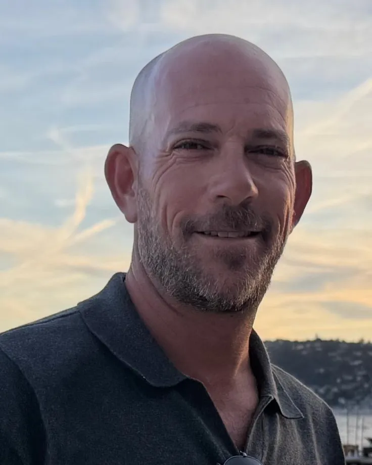 Charlie Drai, co-founder of IGLY Spatial, smiling by the water at sunset